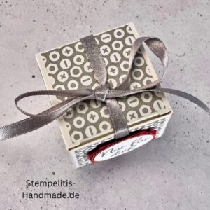 handdekorierte Geschenkschachtel mit Aufschrift „Nur für dich“, Geschenkschachtel mit grauem Muster und rotem Etikett, kleine Geschenkbox mit Satinband, Vorderansicht der Schachtel „Nur für dich“, offene Geschenkbox mit Inhalt, Detailaufnahme Schriftzug „Nur für dich“, stilvolle Geschenkverpackung mit Band